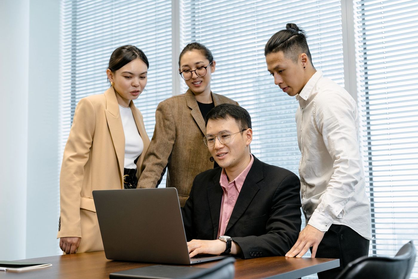 The same team gathered around the manager at a laptop, smiling and working together