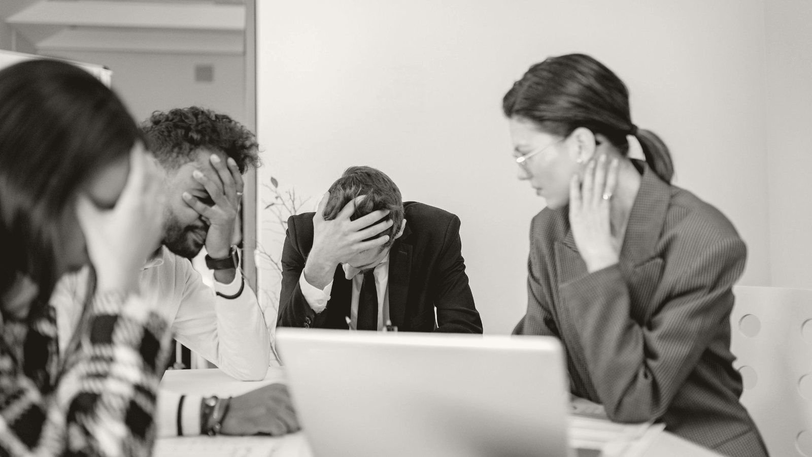 A capable leadership team stuck under pressure around a table — the same collision repeating