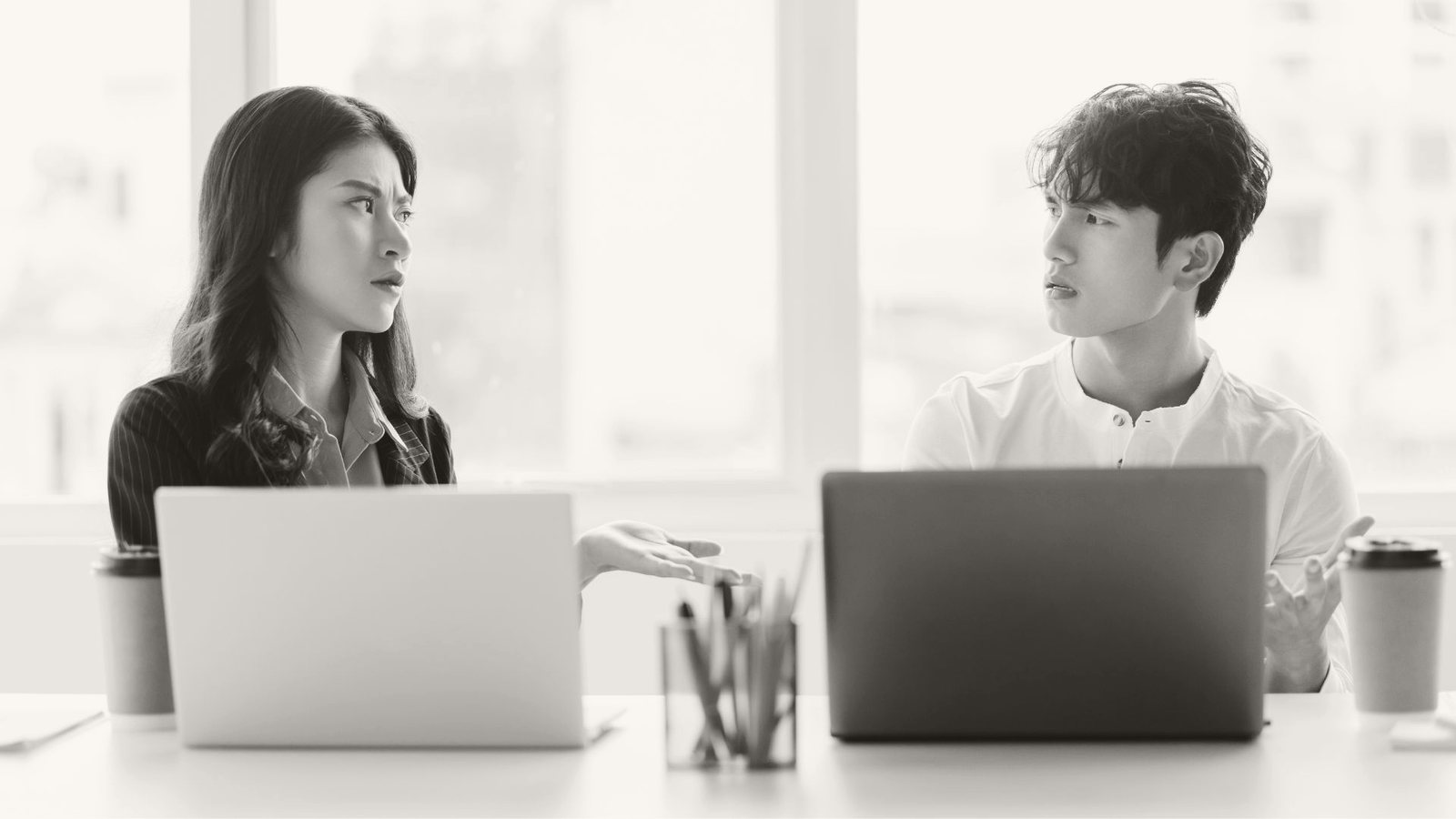 Two strong colleagues misreading each other across a desk — the friction a capable-but-wrong-fit hire creates